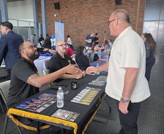 Supervisor Curt Hagman shakes hands with a U.S. Army recruiter at a job fair booth while speaking with recruiters and learning about opportunities.
