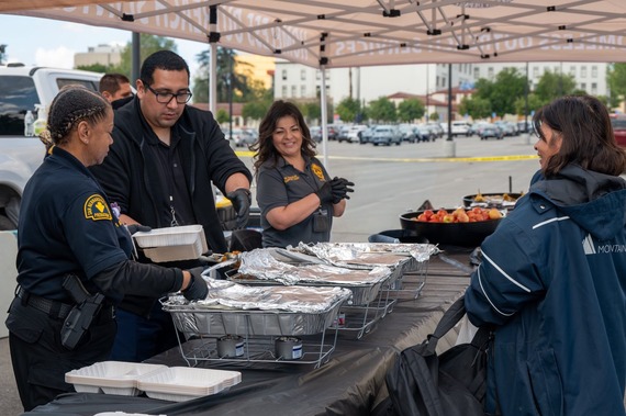 Probation staff and partners serve hot meals under a canopy during a community outreach event.