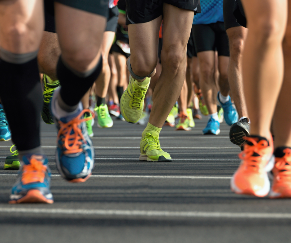 A dozen or so legs and feet of people participating in some sort of competitive run or walk.