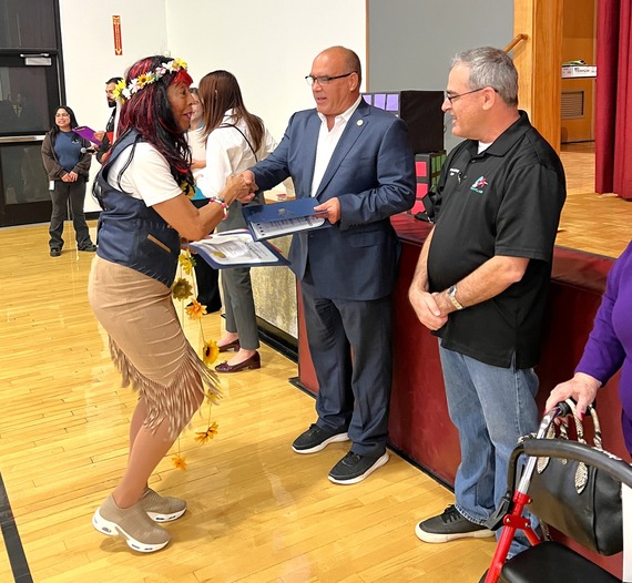 Supervisor Curt Hagman presents a certificate to a participant during a senior event while others look on nearby.