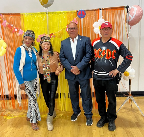 Supervisor Curt Hagman poses with attendees in colorful outfits at a themed senior celebration with bright decorations.