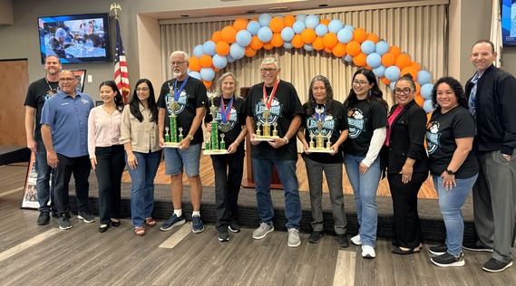 Supervisor Curt Hagman joins participants holding trophies during a group photo at the 2026 Chino Legends closing ceremony event.