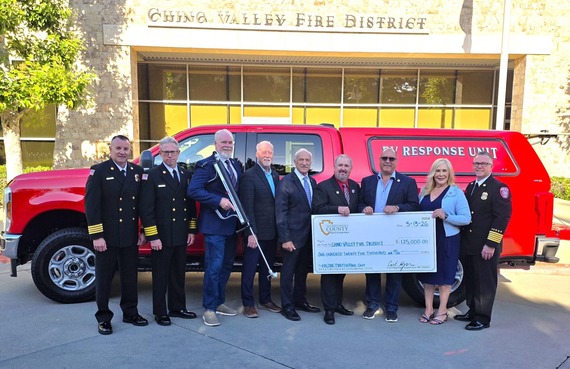 Chino Valley Fire District officials and community leaders in front of a red EV Response Unit truck while holding a $125,000 check.
