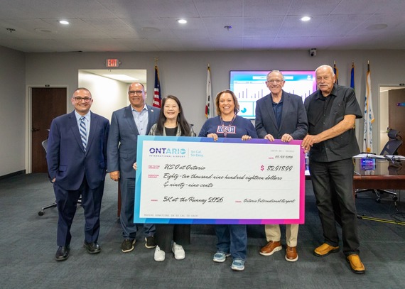 Group of community leaders and airport representatives pose with a ceremonial donation check for $82,918.99 supporting the 5K at the Runway event.