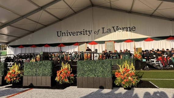 University of La Verne commencement stage decorated with flowers as graduates, faculty, and guests gather for the ceremony.