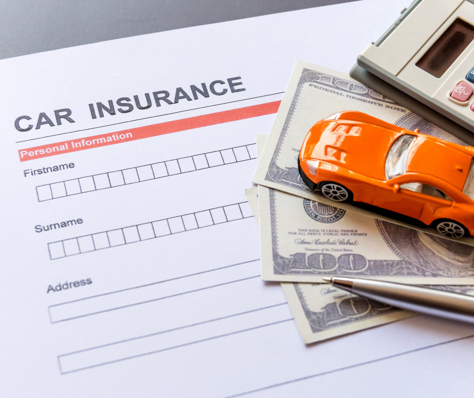 A car insurance application form with several U.S. dollar bills, an orange toy car, a calculator, and a pen resting on top.