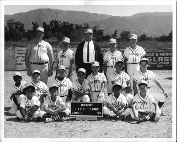 A black and white photo of a baseball team with players, a coach and a Muscoy Little League Comets sign in front of the group.