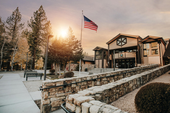 The Big Bear Lake City Hall pictured at sunset with an American flag flying in the foreground.