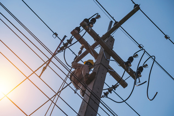 The power lineman uses an insulated tool to open the connection of the transformer from the high voltage distribution system.