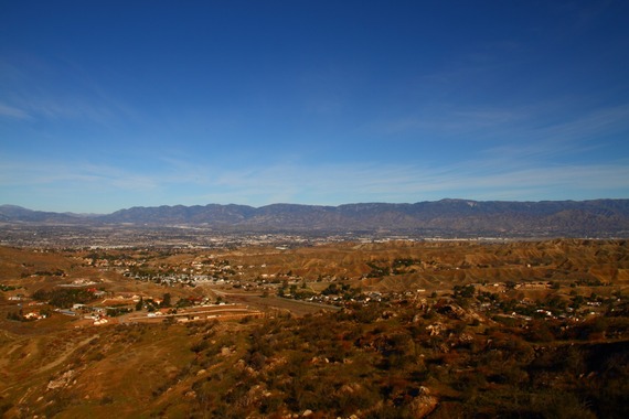 A wide view of Reche Canyon featuring hills and houses surrounded by mountains