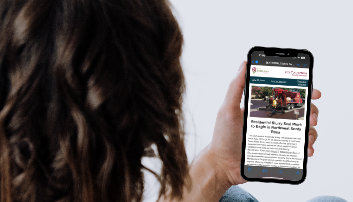 Woman Looking at City Connections Newsletter on Cell Phone_ENG_700x400