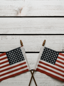 Two crossed U.S. flags on a white wood background