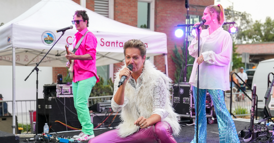An image of the band Neon Velvet performing on stage wearing colorful clothing