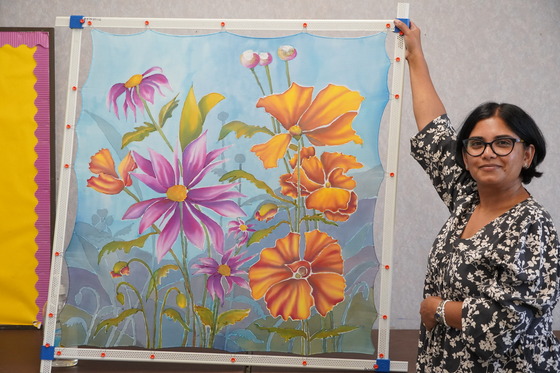 Woman showing a painting of beautiful flowers.