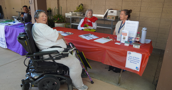 A person talking with two people at an information table during an event. 