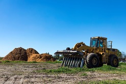A farm with a tractor and mulching piles