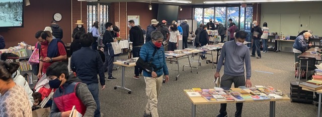 A group of people looking at the Friends Book Sale in the Program Room