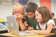 three children looking at a laptop computer