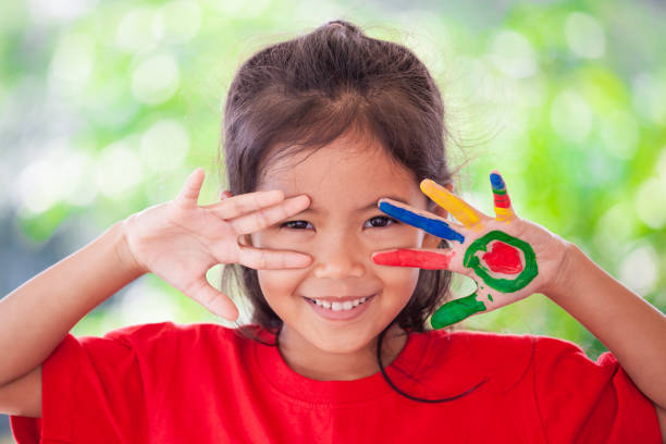 messy art: girl holding her painted hands over her face