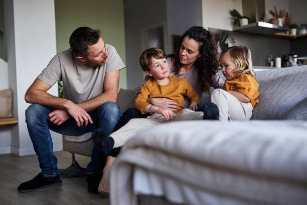 man, woman and two young children sitting on a couch and talking