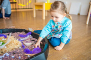 child playing in a sensory sand box