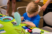 Child painting arm with colorful safe paints 