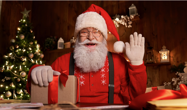 "Santa waving hello holding on to a package with a red bow"
