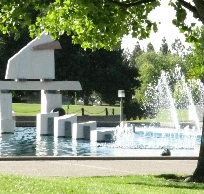 Fountain with geometric white structures in a park.