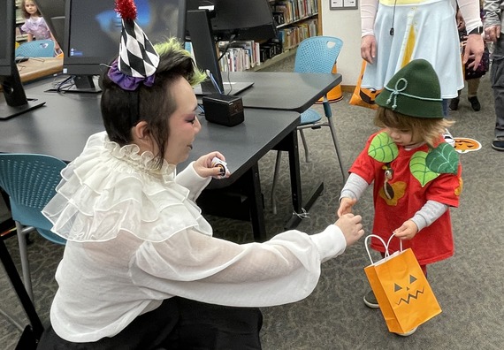 Library staff giving stickers to a child during Halloween Treat Walk