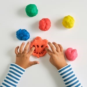 child's hands playing with colorful dough