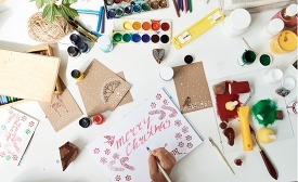 Person writing a card that reads "Merry Christmas"
