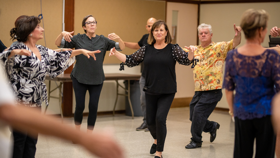 Adults learning ballroom dance steps.