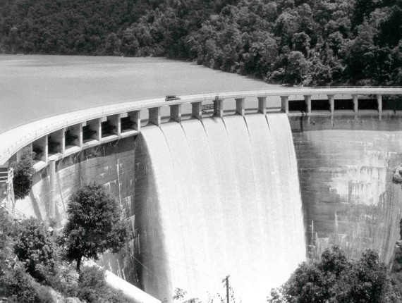 Old Bullards Bar Dam with a car driving across and water spilling below. 