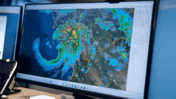 A series of video clips showing a weather forecast, a reservoir releasing water and people sandbagging a levee.