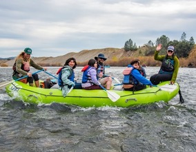 Smiling river guides and fourth grade students on a raft on the Yuba River