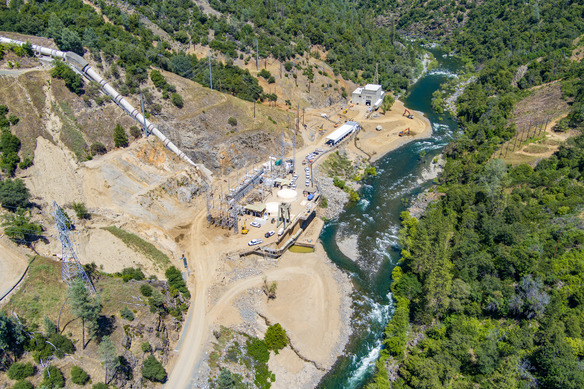 An aerial photo of a hydroelectric power generation facility on a river. 