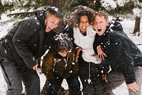 Four individual stand in snow while snowballs are being thrown at them