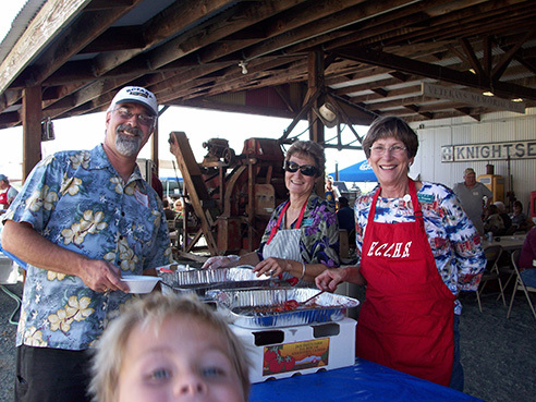 Photo of two people at a barbeque with a kid in the front