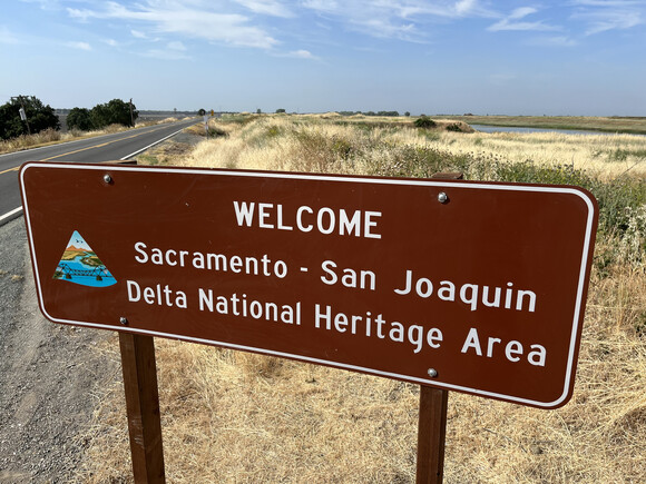 A brown sign welcoming motorists to the Sacramento-San Joaquin Delta National Heritage Area