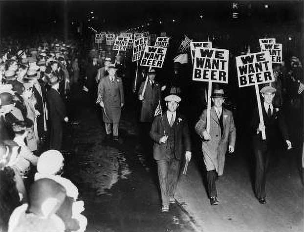 Men in the 1920s march carrying signs saying "We Want Beer"