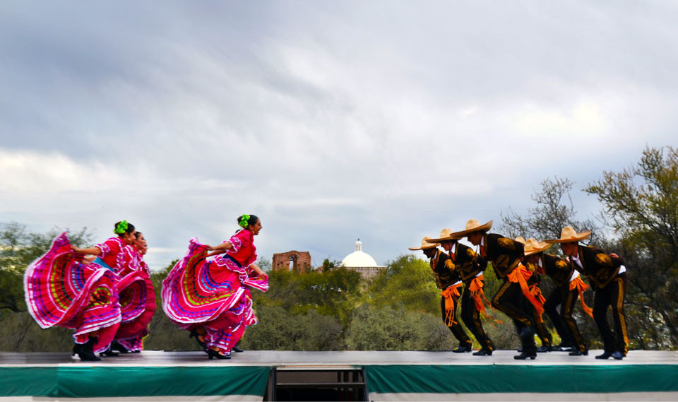 Lines of men and women in traditional Mexican dance garb face each other in Nogales, Arizona