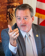 Man at a dais talking and gesturing