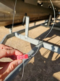 A red DWR Oroville seal indicating a failed watercraft inspection is affixed to a pontoon boat with attached golden mussels. 