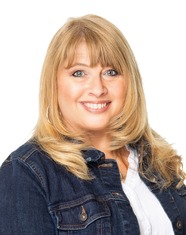 A woman in a denim jacket smiles for the camera