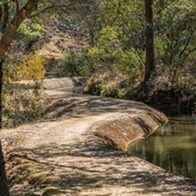 The dirt-covered Brad Freeman Bike Trail winds to the left of a water canal. 