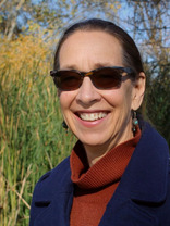 Woman smiling with a backdrop of bulrush and trees