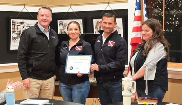 Two men and two women posing with a certificate of recognition