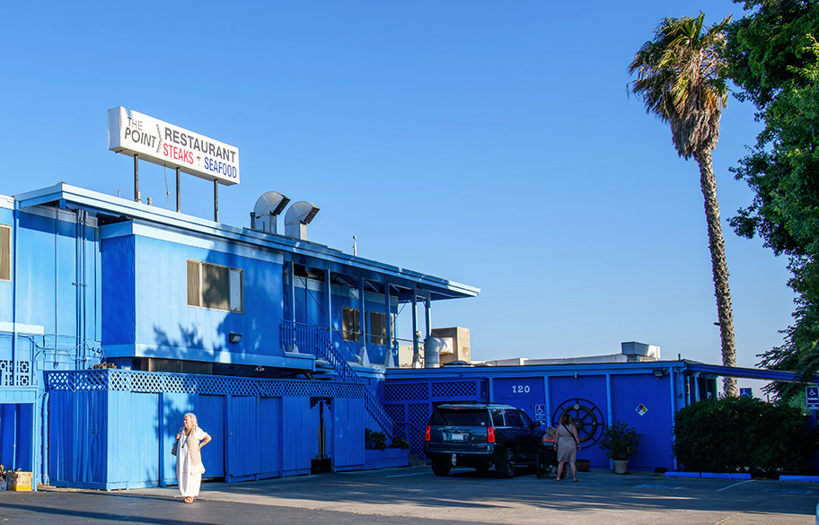 a restaurant with "steaks & seafood" sign and a palm tree in the background