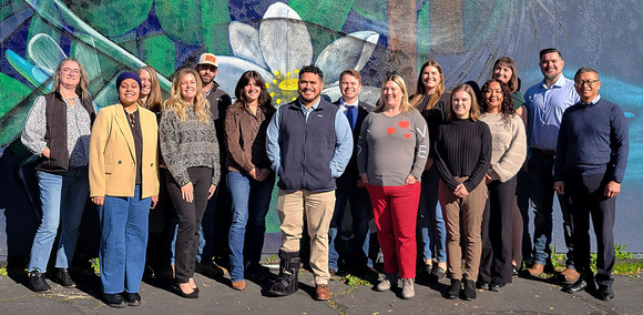 Group of adults posing in front of an outdoor mural