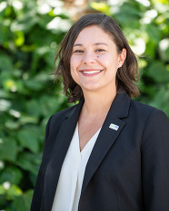 Portrait of a smiling woman standing in front of a wall of ivy